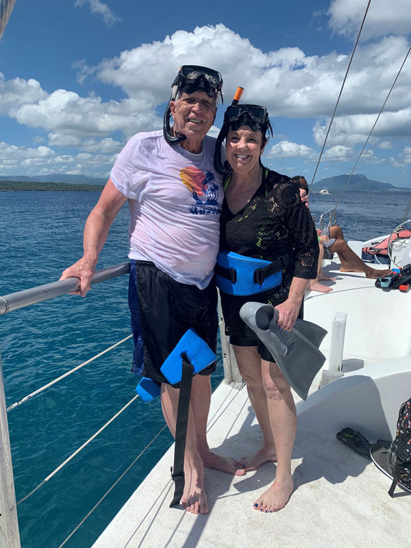 A couple smiling on a boat wearing snorkeling gear