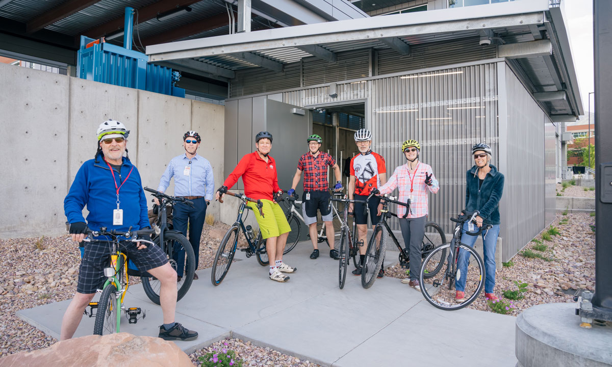 Seven employees pose with their bikes in front of the new bike storage facility.