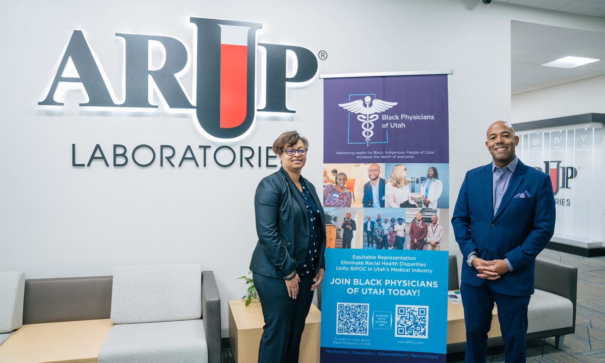 Kamisha Johnson-Davis and Richard Ferguson stand in front of an ARUP banner