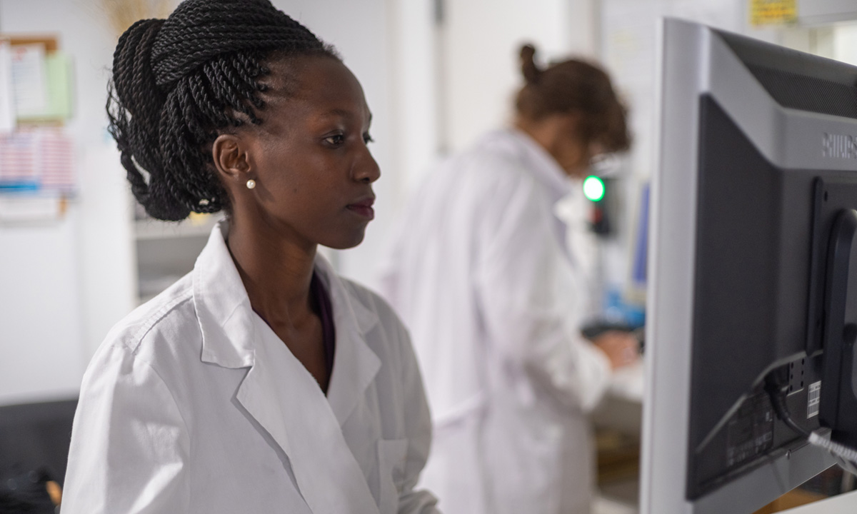 A woman in a lab coat looks at a computer screen