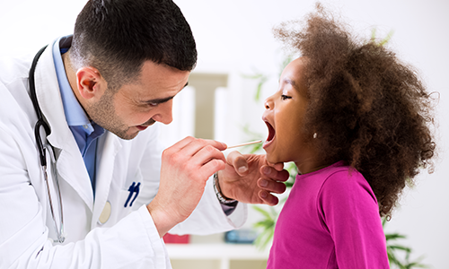 A male clinician examines the throat of a child