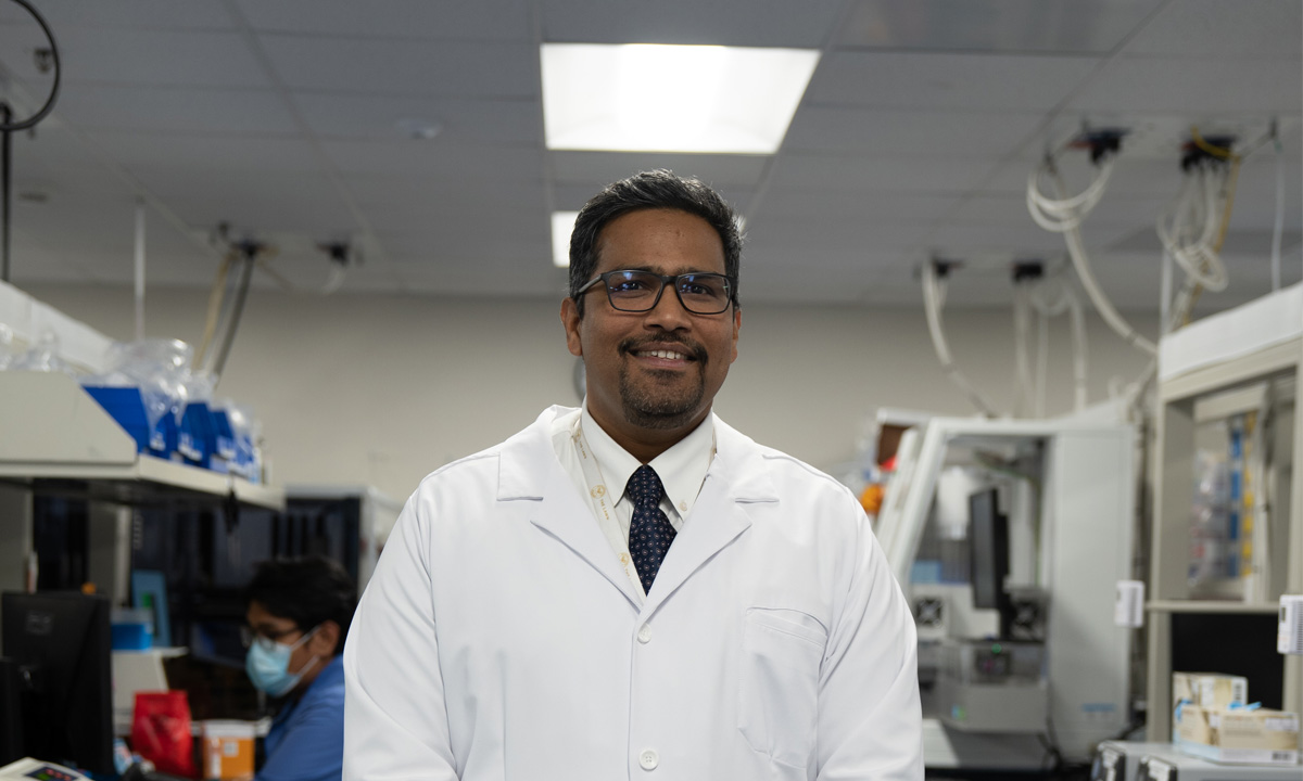 Dr. Madhu Menon stands in a lab.