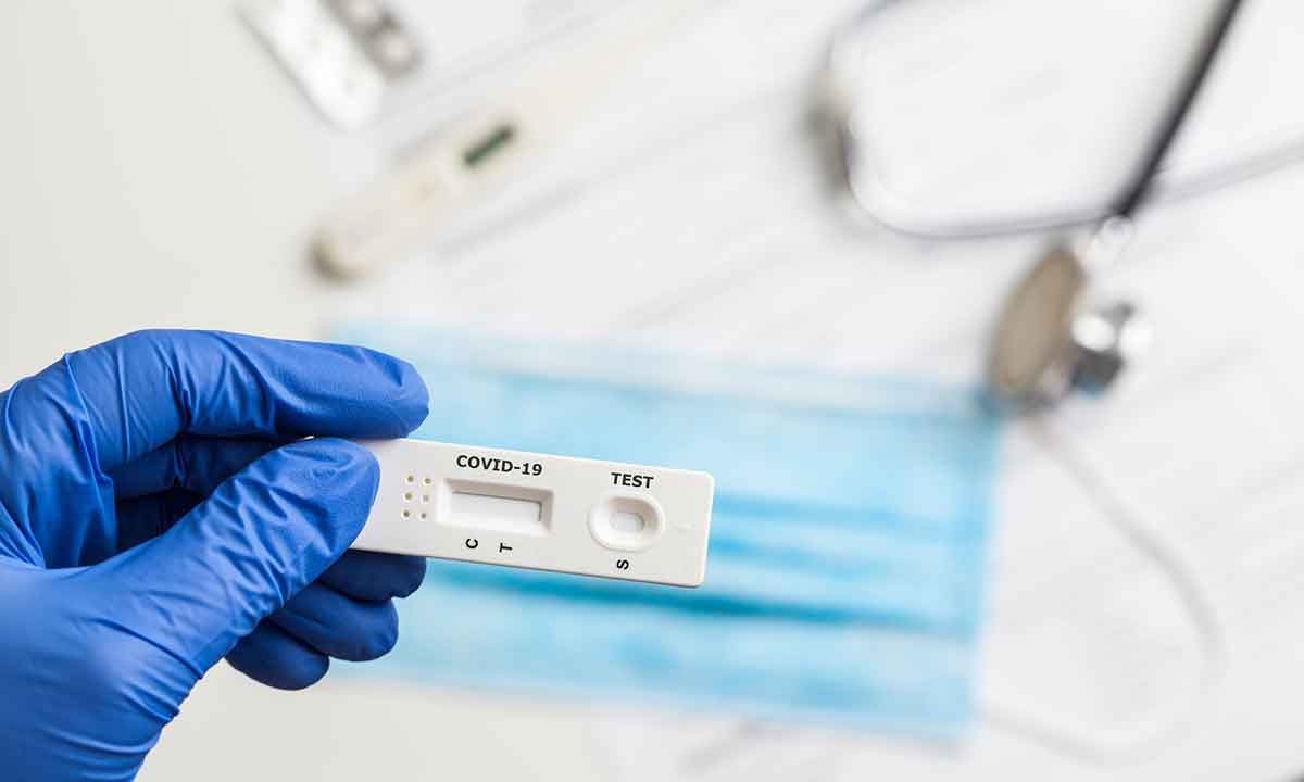 A gloved hand holds COVID-19 testing specimen.