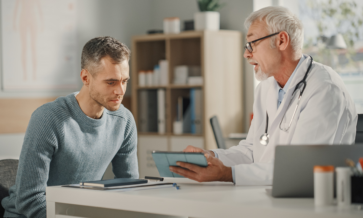 A male clinician discusses something with a male patient