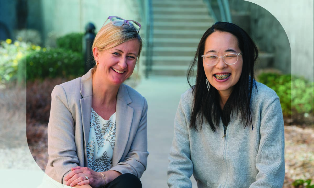 Agata Golcz-McGill, left, and Kanako Yumioka sit outside on steps of a walkway.