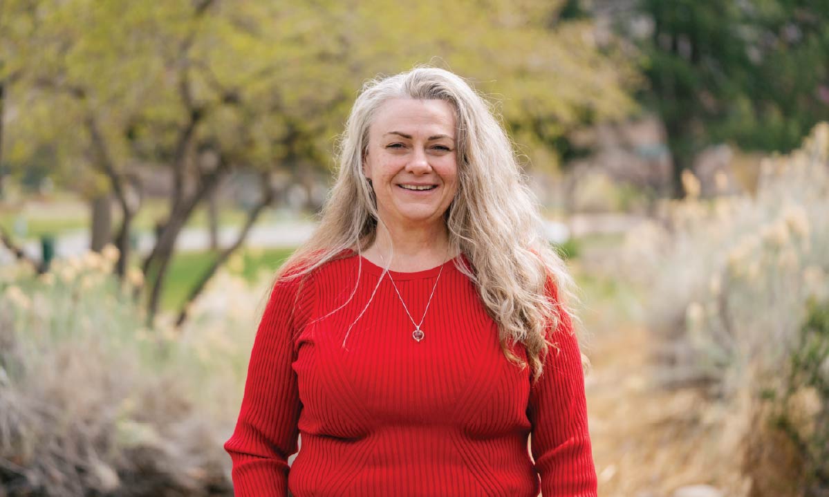 Misty Segrest stands outside among trees and ornamental grasses.