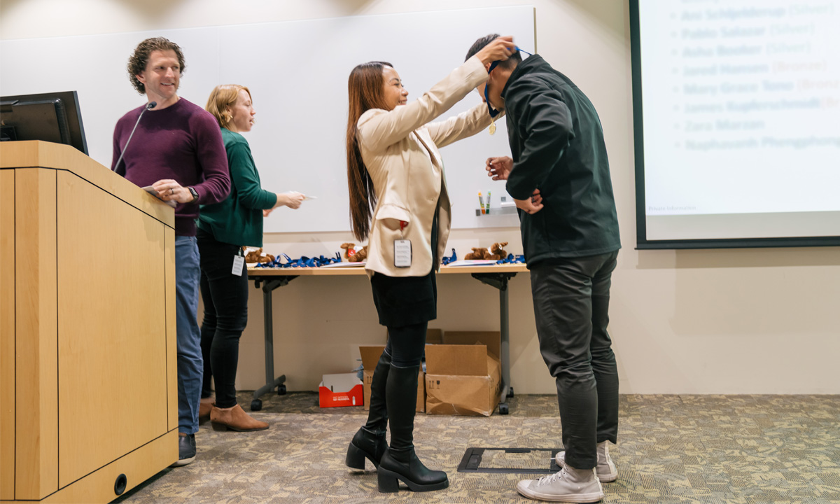 Ahmed Mohammed accepts an award from Ligaya Kuiken. Tyler Tinling and Tiffany Harris look on.