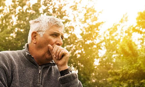 photo of man with white hair coughing