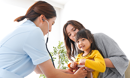 Female clinician examining young girl being held by adult woman