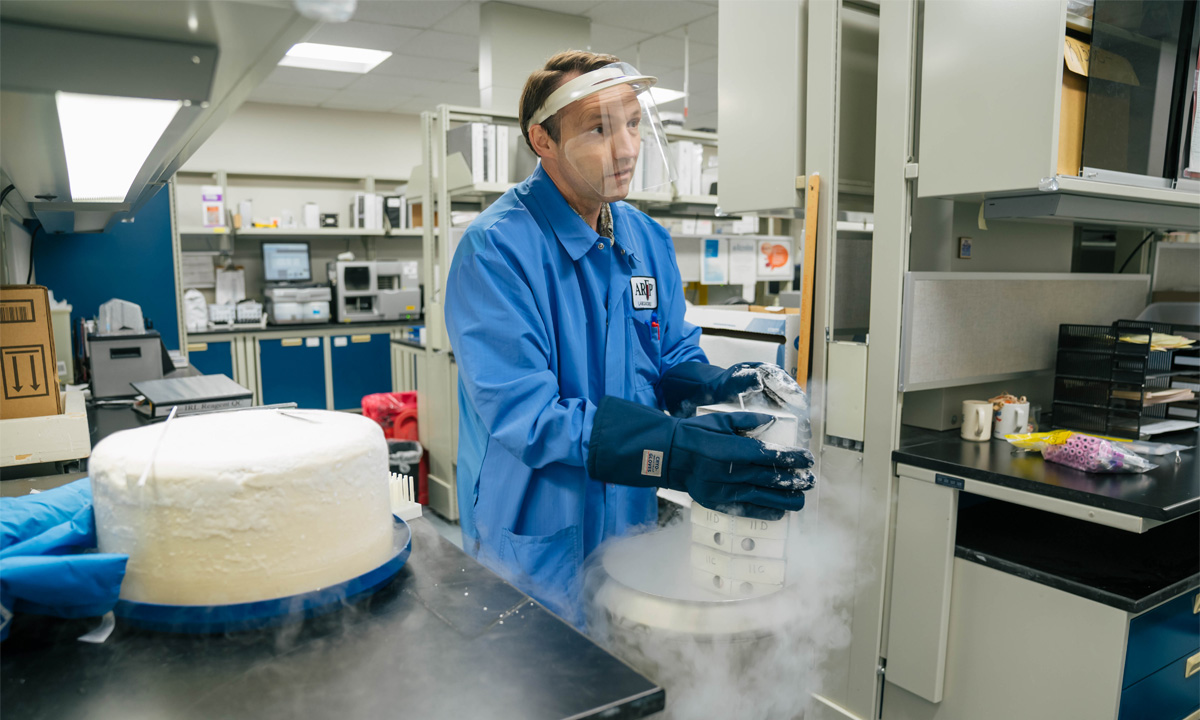 Noel Pusey, wearing protective gear, works with a machine in a lab