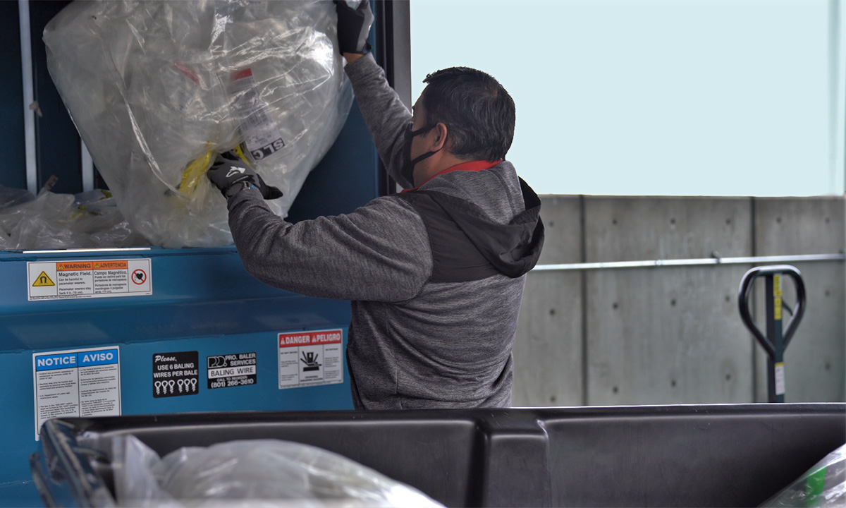 A man empties recyclables into a recycling bin