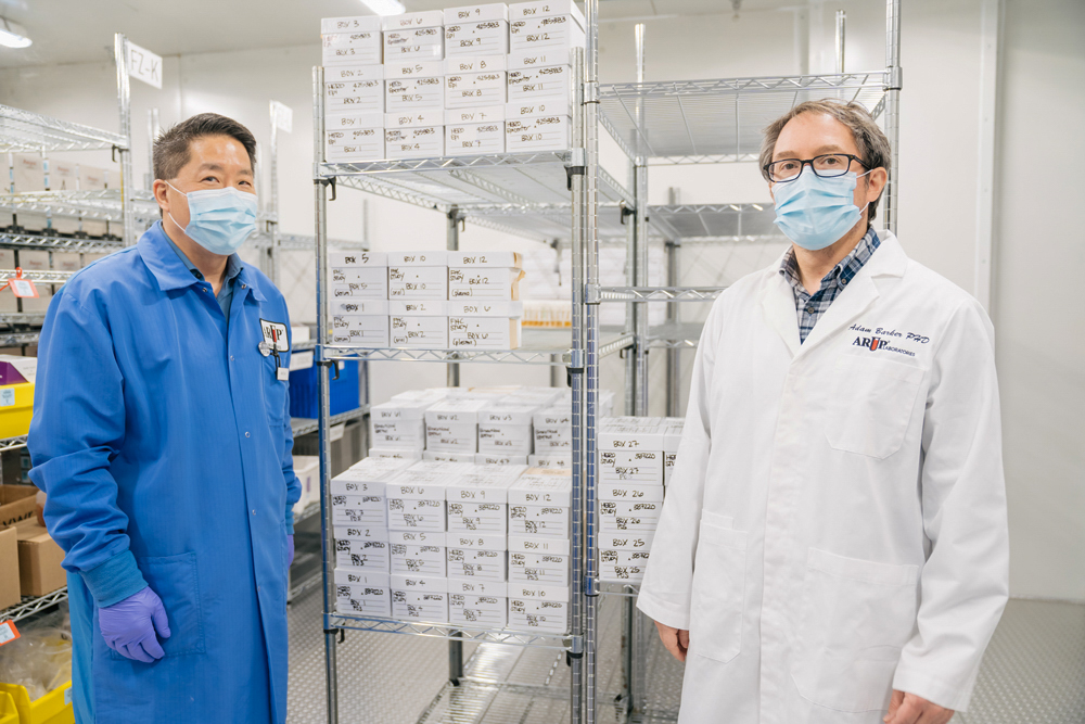 Lincoln Hirayama and Adam Barker wear face masks in front of testing supplies