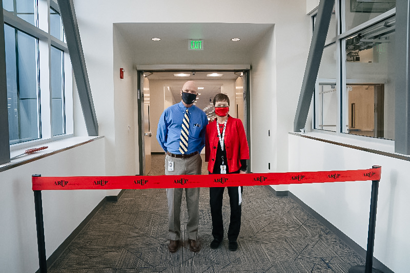 President Andy Theurer and CEO Sherrie L. Perkins, MD, PhD, stand behind a ribbon across a hallway