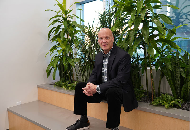 CEO Andy Theurer sits on steps in front of potted plants