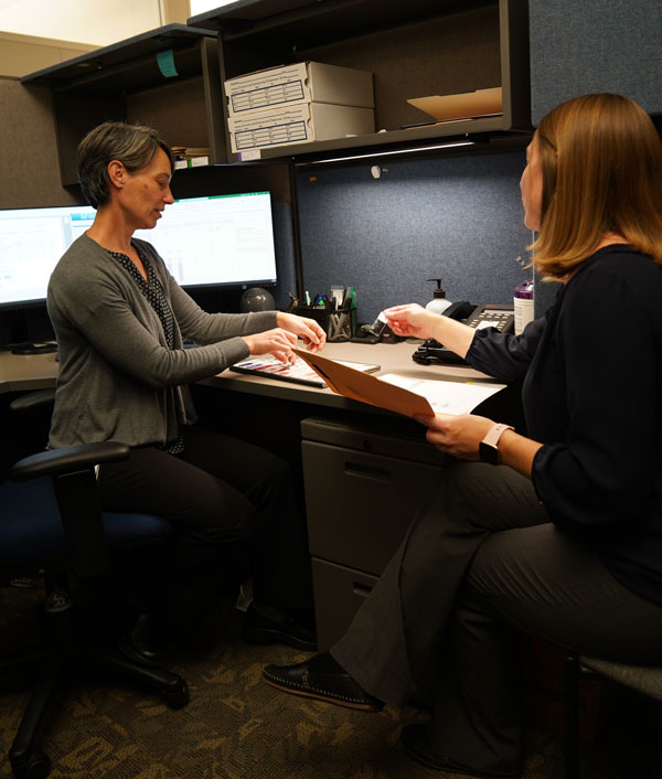 Emily Coonrod and Rayna Lofgren sit at a desk talking