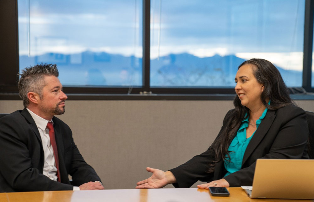 Two people face each other talking at a table