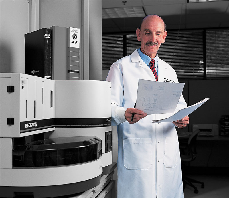 Harry Hill looks at a sheet of paper in front of lab equipment