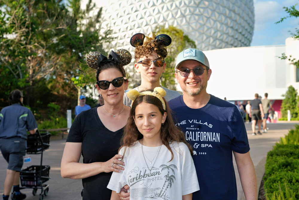 A family poses with the Epcot Center in the background at Disney World