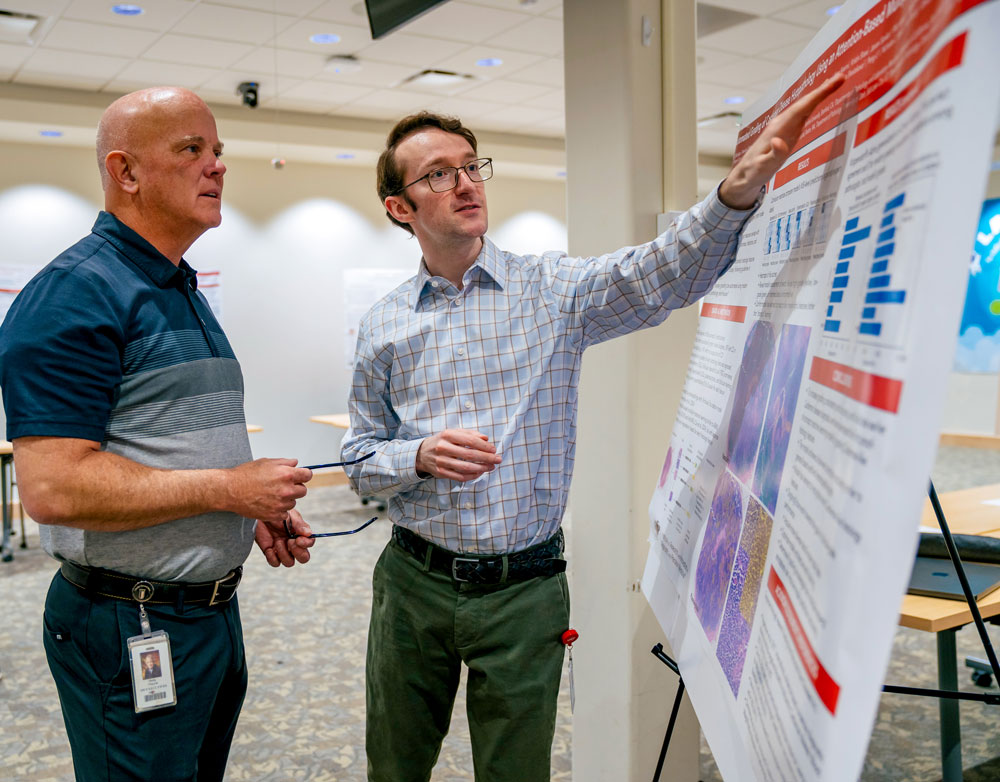 Two men look at a large printed display
