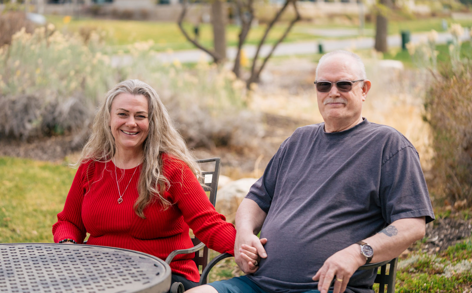 A couple holding hands at a table outdoors